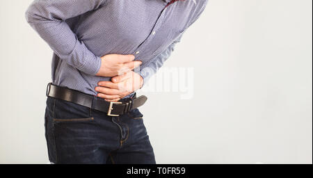 A man suffers from abdominal pain. Abdominal pain. The guy in the seeming clothes holding belly with hands. Stock Photo