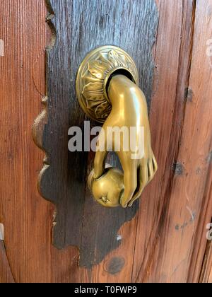Detail of beautiful historic brass hand shaped Spanish door knocker on wooden door entrance to Palace courtyard, Palma de Mallorca Stock Photo
