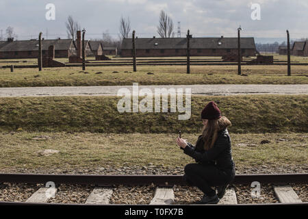 Tourist making a photo on the Railway leading to main entrance of Auschwitz Birkenau concentration camp, Poland March 12, 2019 Stock Photo