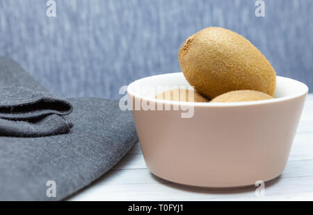 Kiwi on a wooden table next to a dark cloth Stock Photo