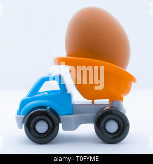 Colorful toy truck with a chicken egg in the back on a white background Stock Photo