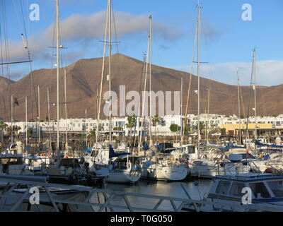 Variety of yachts and boats moored up at the Marina Rubicon in Playa Blanca with Lanzarote's volcanic landscape in the background Stock Photo
