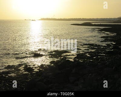 Looking out to sea, early evening in Lanzarote, when the setting sun casts a yellow glow on the water Stock Photo