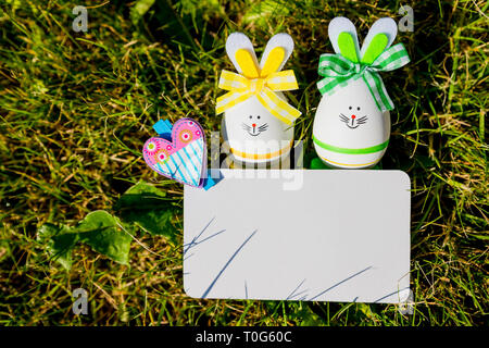 Blank greeting card with small easter eggs in the grass.Easter eggs on meadow. Spring holidays concept .Easter composition with easter eggs .Mockup Stock Photo