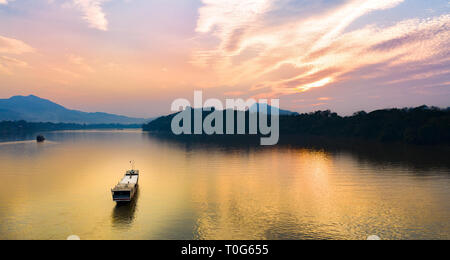 View from above, stunning aerial view of a tourists boat sailing along the Mekong river at sunset. Stock Photo