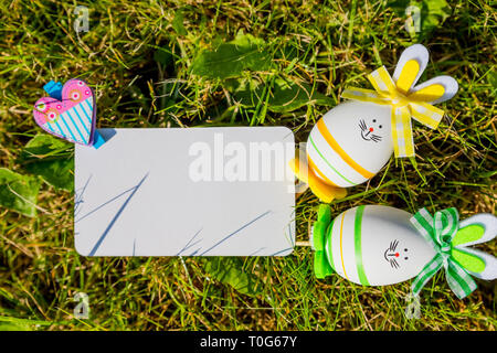Easter greeting card mock up with bunny eggs on green grass background. Creative greeting concept.Blank card, Layout with copy space for your text Stock Photo