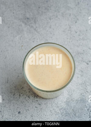 Healthy drink golden turmeric latte in glass cup. Yellow homemade latte on gray background. Detox turmeric tea latte. Copyspace for text Top view or flat lay. Vertical. Stock Photo