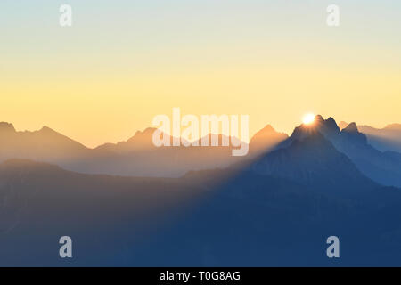 Colorful sunrise in the mountains. Silhouettes of mountain ranges with yellow sky. Allgaeu Alps, border region of Germany and Austria. Copy space Stock Photo