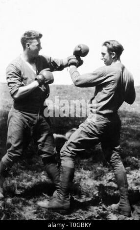 Two young men engage in a boxing match out in a field, ca. 1930. Stock Photo