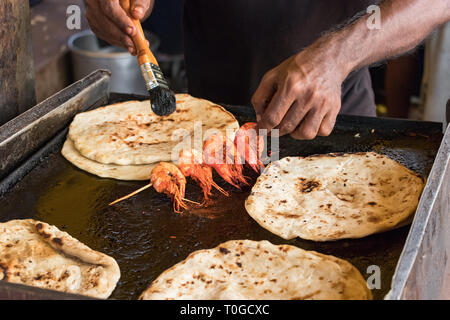 Male hand of a cook, cooking prawns with pol roti flat bread tn the food street market of Galle Face Dr st in Colombo, Sri Lanka. Stock Photo