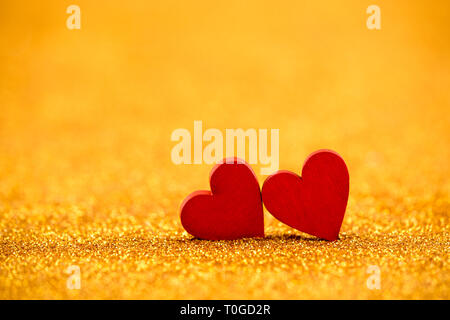 Two red hearts on golden glitter background in love concept Stock Photo