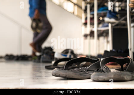Sandals outside the main entrance of a mosque with a prayer taking off his shoes as blur background in Male, Maldives. Stock Photo