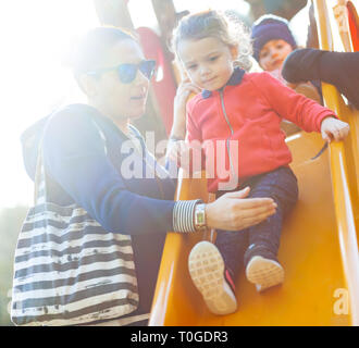 Aunt and nephew play on the slide at the park in a spring day. Stock Photo