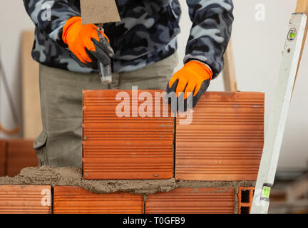 Bricklayer industrial worker installing brick masonry on interior wall with trowel putty knife Stock Photo