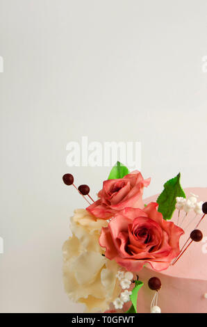 Cake decorated with pink rose flowers and leaves on white background. Stock Photo