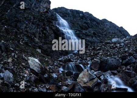 Large mountain waterfall in the mountains on the dark wet rocks, evening landscape long exposure Stock Photo