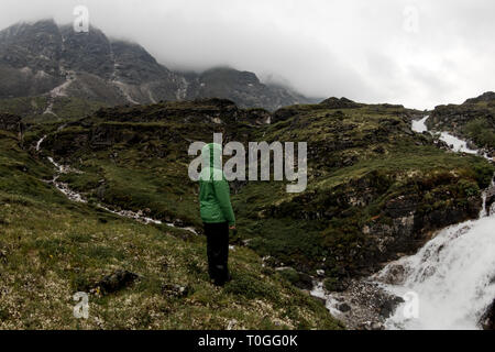 Woman of tourists standing by the mountain river on a foggy summer day in the rain Stock Photo
