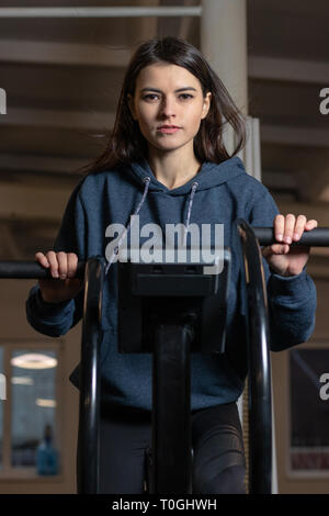 The girl is engaged on a crossfit exercise bike in the gym Stock Photo
