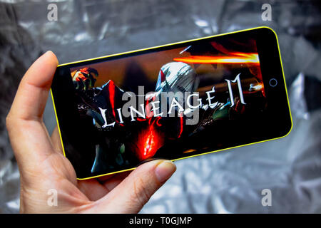 Berdyansk, Ukraine - March 16, 2019: Hands holding a smartphone with lineage 2 revolution game on display screen. Stock Photo