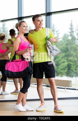 sportive couple with water bottles and bags in gym Stock Photo