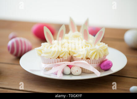 cupcakes with easter eggs and candies on table Stock Photo