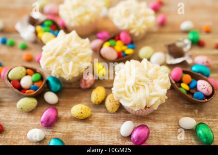 cupcakes with chocolate eggs and candies on table Stock Photo