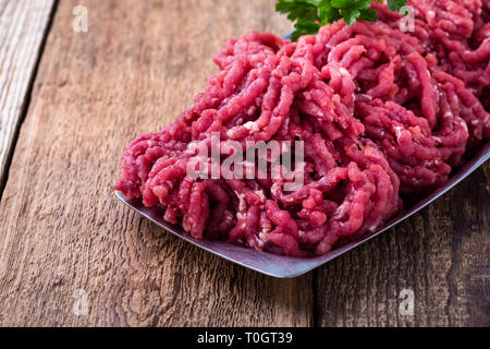 Minced beef, raw ground meat with cooking ingredients on rustic wooden table, close up, selective focus Stock Photo