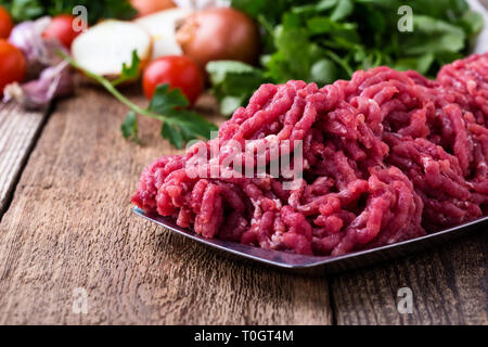 Minced beef, raw ground meat with cooking ingredients on rustic wooden table, close up, selective focus Stock Photo