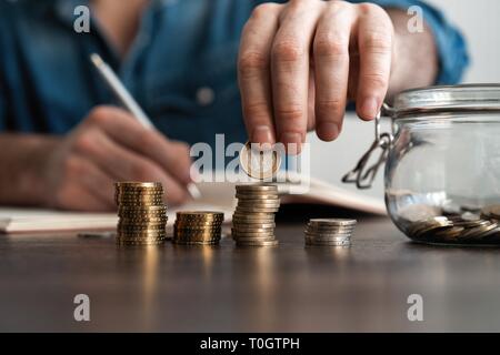 business accounting with saving money with hand putting coins in jug glass concept financial Stock Photo