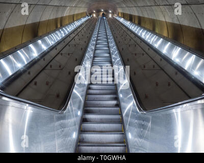 Washington DC, United States - 3 March 2019. Long escalator leading up from Adams Morgan Metro station through concrete tunnel illuminated in cold, me Stock Photo