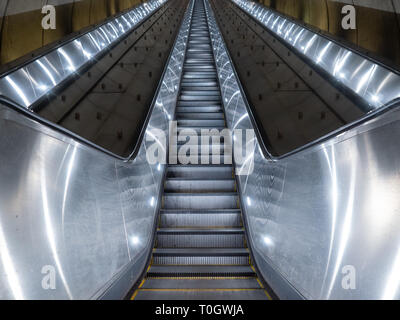 Washington DC, United States - 3 March 2019. Long escalator leading up from Adams Morgan Metro station through concrete tunnel illuminated in cold, me Stock Photo