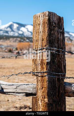 Close-up of barbed wire fence & wooden fence post; ranch in Central Colorado; USA Stock Photo