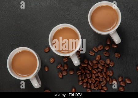 Three cups of coffee with milk on dark background. Top view Stock Photo