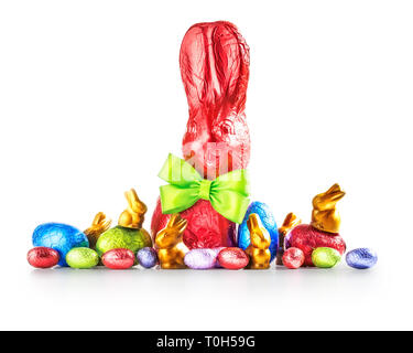 Chocolate easter eggs, rabbit with bow wrapped in coral color foil, small bunnies and colorful candies isolated on white background. Holiday design el Stock Photo