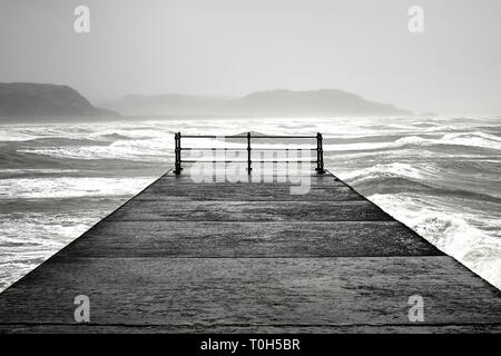 Waves crash past the breakwater in Criccieth in North Wales during storm Hannah Stock Photo