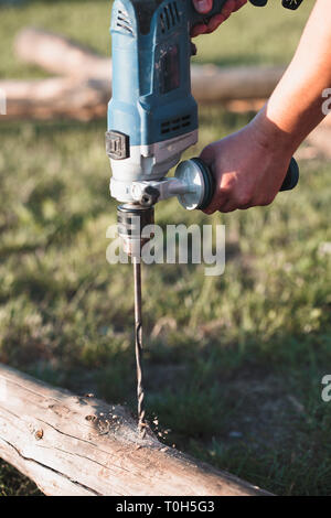 Man drilling hole in timber while working in garden Stock Photo