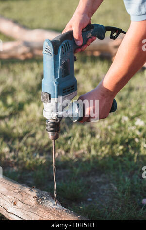 Man drilling hole in timber while working in garden Stock Photo