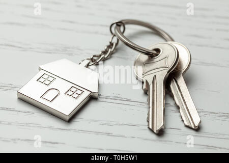 Keychain house and keys on white wooden background. Stock Photo