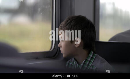 serious boy is traveling by train looks out the window Stock Photo