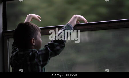 Happy boy is traveling by train in the evening, looking out the window Stock Photo