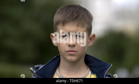 portrait of a serious boy with a tence glance looking at the camera, close-up heavy face Stock Photo