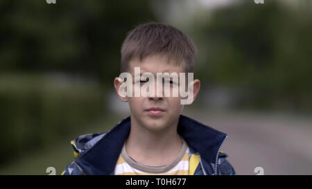 portrait of a serious boy with a tence glance looking at the camera, close-up heavy face Stock Photo