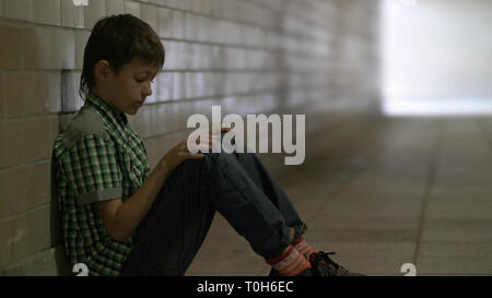 sad boy sits on the floor in a tunnel in deep depression Stock Photo