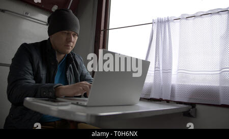portrait young man on the train, prints on laptop Stock Photo