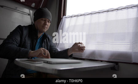 young man in a train starts working on laptop Stock Photo
