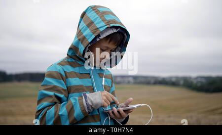 Boy listening to music from your phone, boy in a field on the mountain in the evening Stock Photo