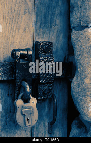 Old rusty metal door latch and padlock with colour toning Stock Photo