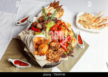 Mixed grill meat, fried vegetables and grilled salmon fish fillets decoration in warm dish. Assorted delicious grilled kebab served with herbs on plat Stock Photo