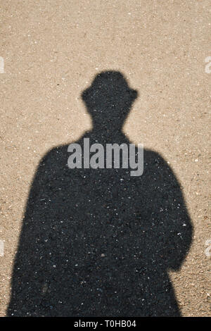 shadow of a man with trilby hat on the asphalt Stock Photo