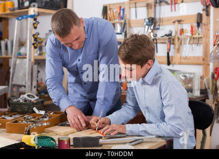 happy germany adult father teaching son сarpentry in the garage Stock Photo